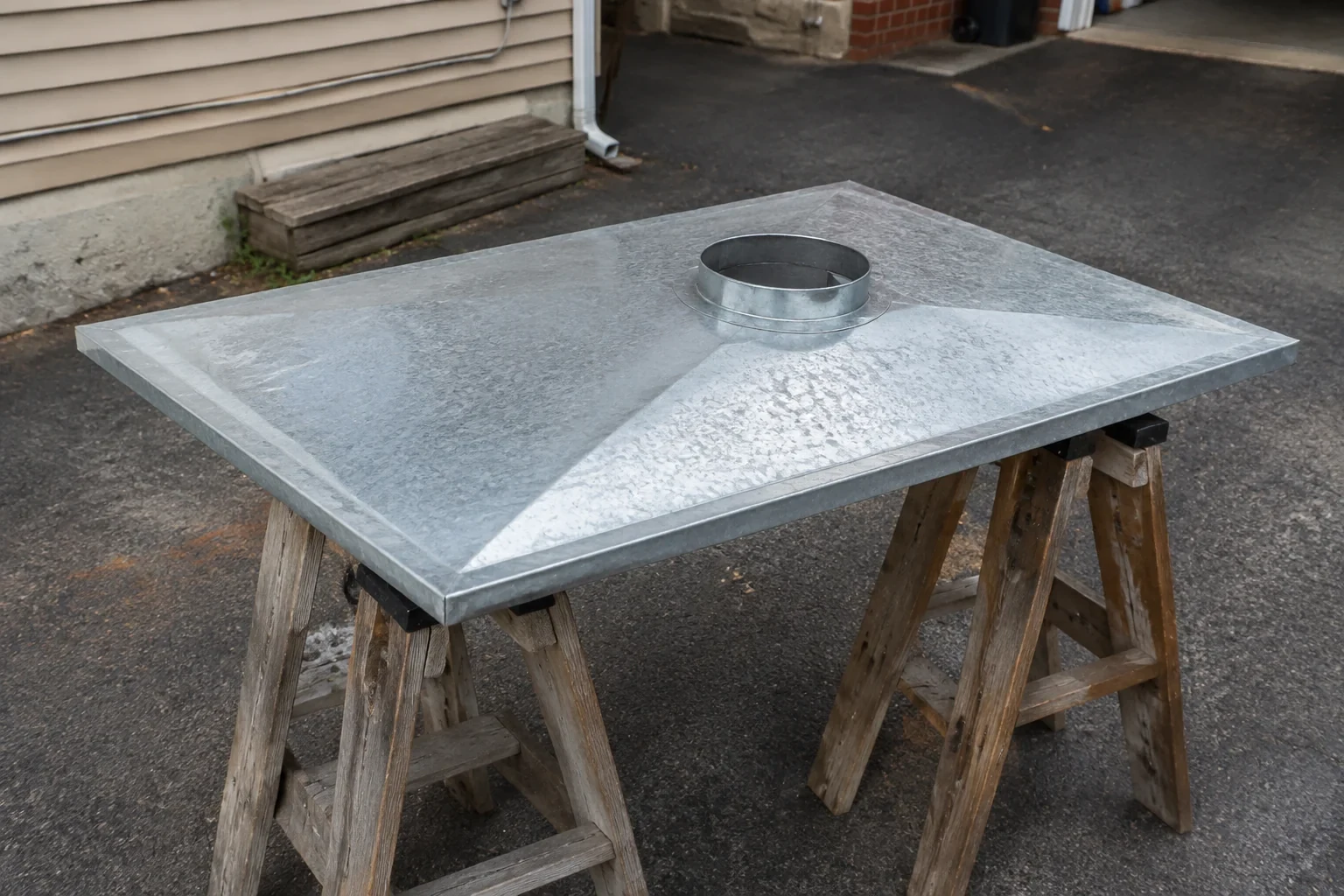 Detached metal chase cover supported on sawhorses.