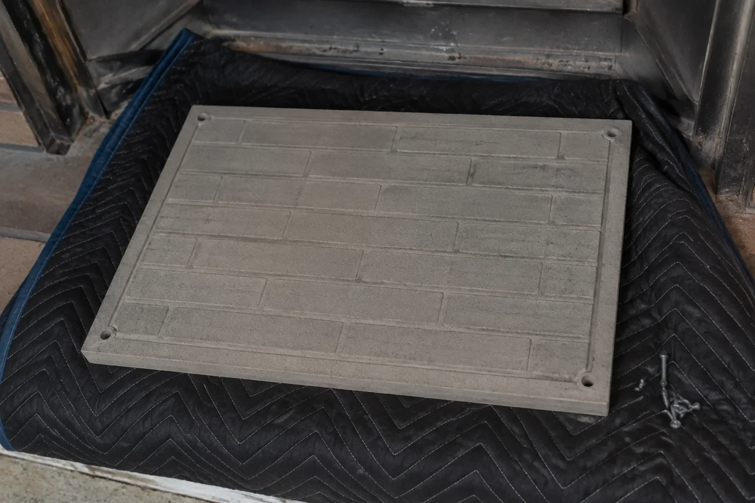 Detached refractory panel on a mat near a fireplace.